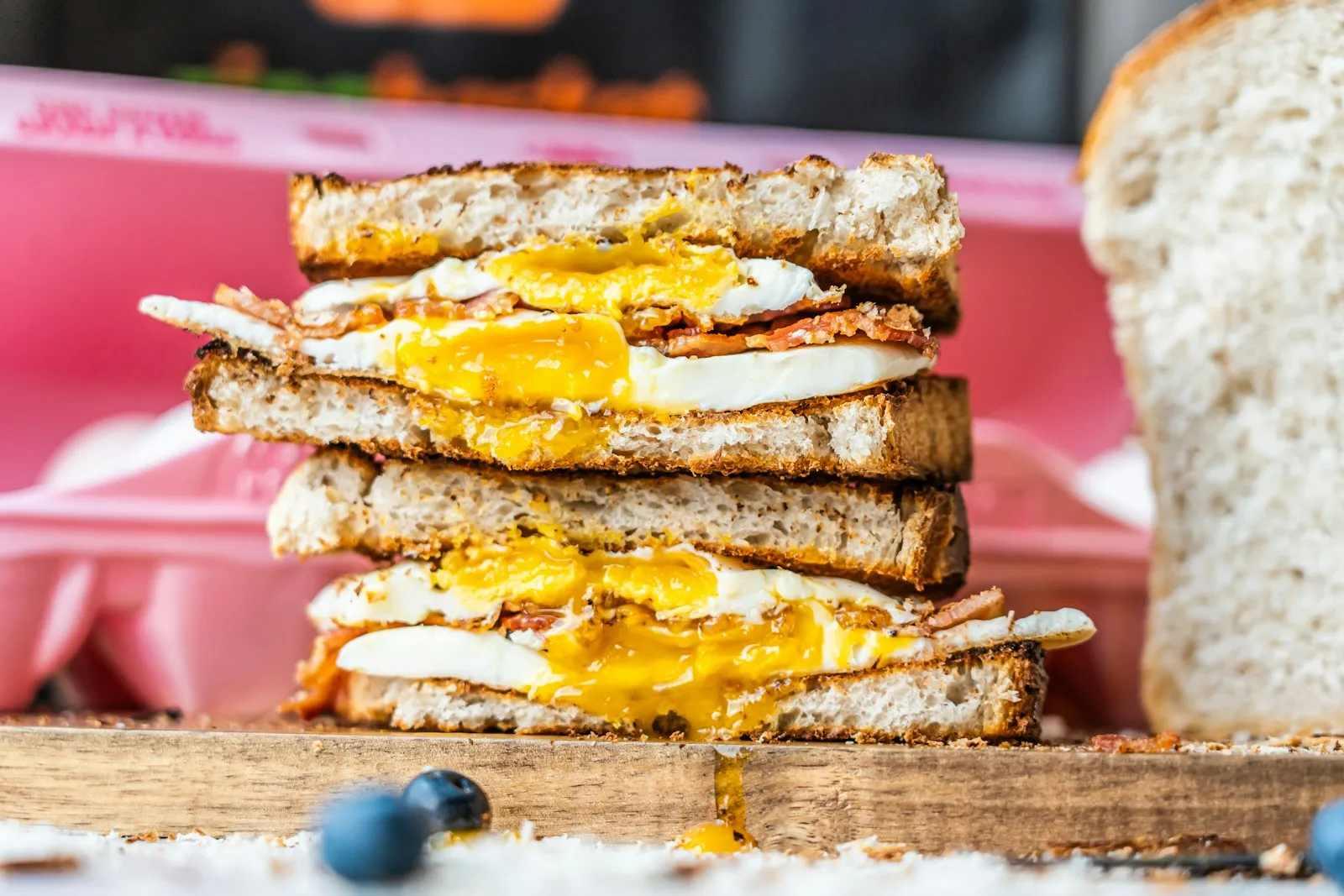 A stacked bacon, egg and cheese breakfast sandwich with a runny yolk.