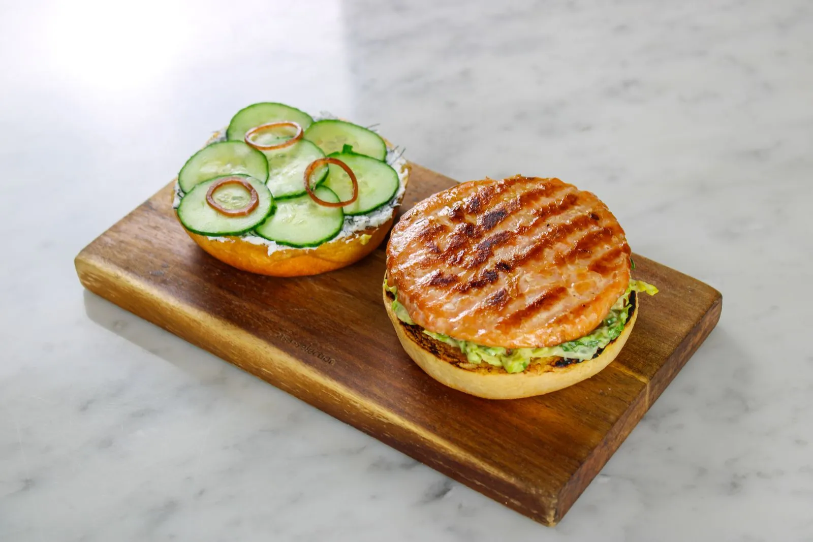 Representative griddled fish sandwich on a toasted bun.