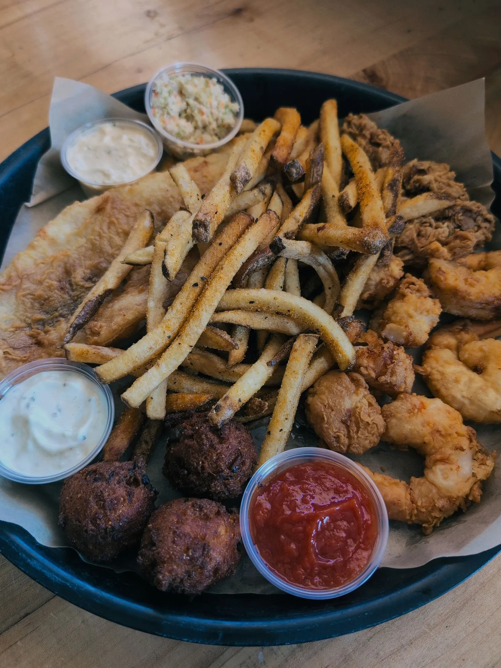 Representative fried seafood platter with fries, shrimp, and hush puppies.
