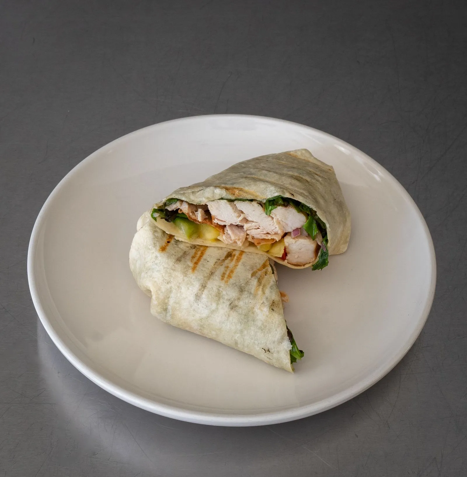 Representative grilled chicken wrap cut in half, showing the filling.